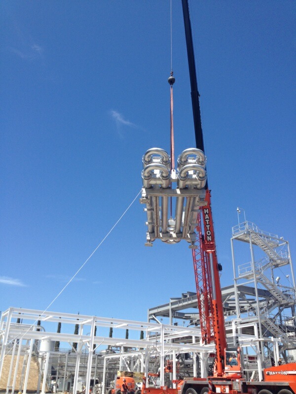 Industrial stainless fabrication being lifted into place by crane